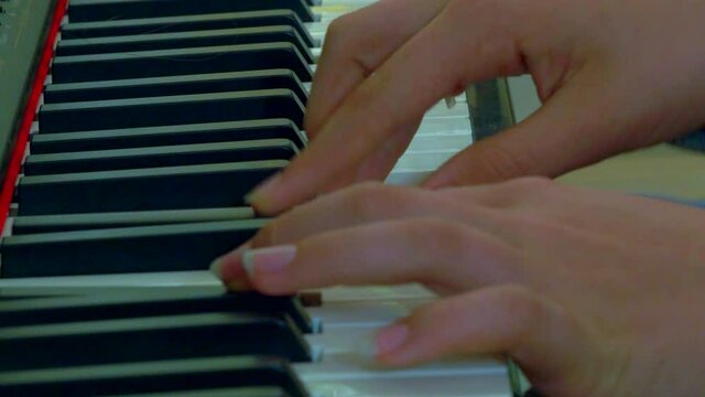 Close up of fingers on a piano key board playing music.
