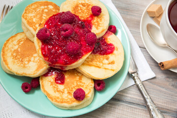 Delicious pancakes with raspberry jam, with fresh tea.