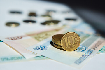 Russian banknotes rubles and a coin with a face value of 10 lie on a white surface. The concept of Economics.