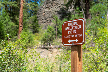 A stay on trail sign posted in a natural revegetation project area along the walking path at the Bowl and Pitcher area of Riverside state park in Spokane, Washington, USA