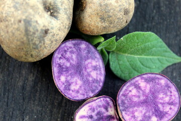 Obraz na płótnie Canvas Purple potato tubers close-up on a board, selective focus.