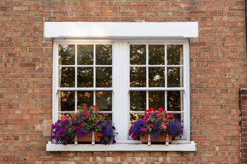 Fototapeta na wymiar the windows of a victorian house with window boxes and bright flowers