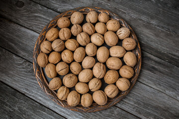 Juglans regia in a copper dish on an old wooden background close-up, top view