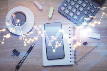 Multi exposure of forex graph hologram over desktop with phone. Top view. Mobile trade platform...