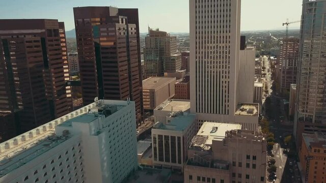 Cinematic aerial/drone shot moving through downtown Phoenix Arizona showing rooftops and street