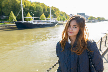 Young beautiful Asian woman standing in pier with vintage black boat in the river