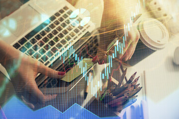 Fototapeta premium Double exposure of businesswoman hands typing on computer and financial graph hologram drawing. Stock market analysis concept.