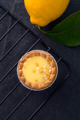 Lemon tartlets, minimalistic top view on dark stone