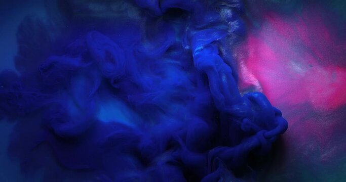 Abstract background. Color Burst - light and deep blue color explosion fluid ink paint particles slow motion isolated on pink background creating beautiful clouds of paint. Hypnotic art creation