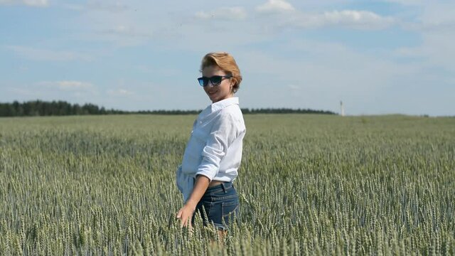 stylish young girl in denim shorts and sunglasses walks on a summer day in a wheat field hd
