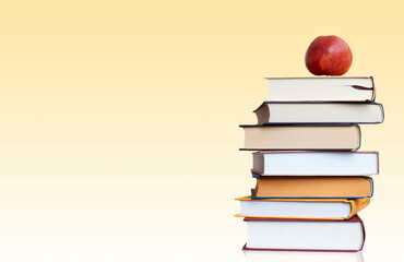stack of books with red apple on the yellow background with copy space