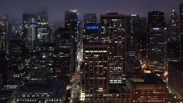 Scenic fog is covering illuminated skyscrapers towers. Business capital, Silicon Valley, United States of America. Cinematic aerial panorama of beautiful downtown San Francisco at night. 4K drone