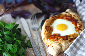 Selective focus. Khachapuri in Adjarian. Fresh homemade hot khachapuri with egg. Georgian cuisine. Khachapuri with fork and knife. Cheese bread.