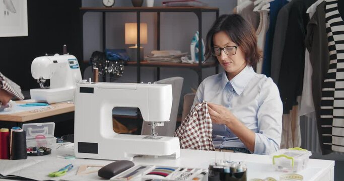 Group of competent fashion designers sitting at their workplace and tailoring clothing. Concept of working process and coworking.