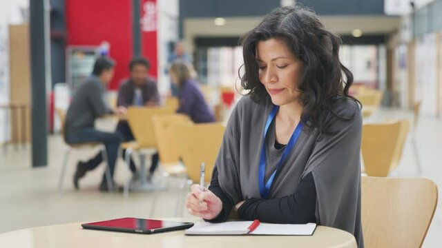 Mature female teacher or student with digital tablet working in college hall - shot in slow motion