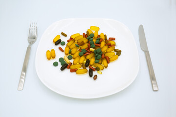 Many different weight loss pills and supplements as food on white plate