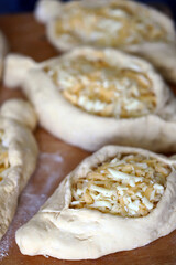 Selective focus. Adjarian khachapuri before baking. Fresh homemade khachapuri with cheese filling. Georgian cuisine. Cheese bread.