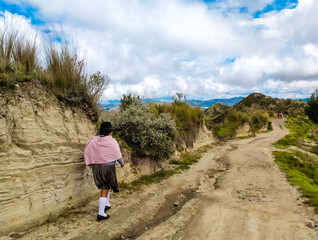 Fototapeta premium A local Ecuadorian woman walks a path in the mountains