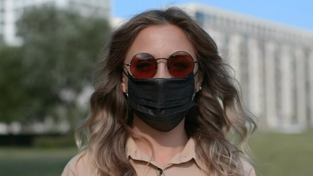 portrait of a girl in a protective black mask and sunglasses in the city, coronavirus concept