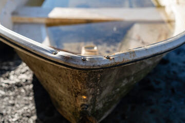 Old rusty dingy boat washed up on shore, full of water
