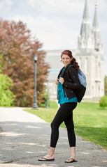 Beautiful female student, with red hair, wearing backpack on campus