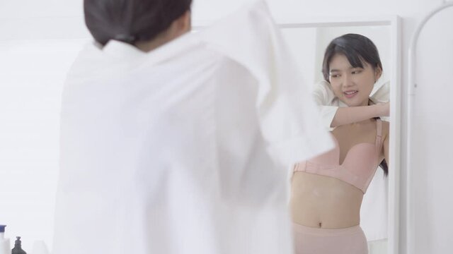 Beautiful young asian woman happy in underwear try on shirt looking mirror with resting at home, beauty asia girl sexy in lingerie is figure fit wearing clothes fashion with preparation in the room.