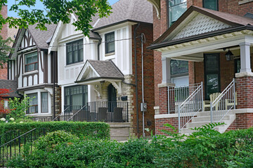 Residential street with large detached brick houses and shady front yards