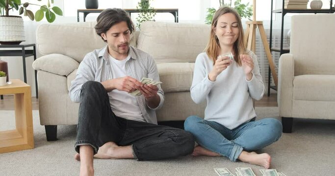 Couple counting money while woman is snatching dollar bills from husband and allocating for future expenses