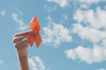 Hands holding orange Ribbon over blue sky,  Leukemia cancer and Multiple sclerosis, COPD and ADHD...