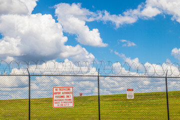 warning signs on a fence with razor wire