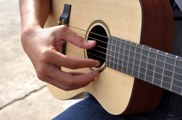 A man sitting picking acoustic guitar