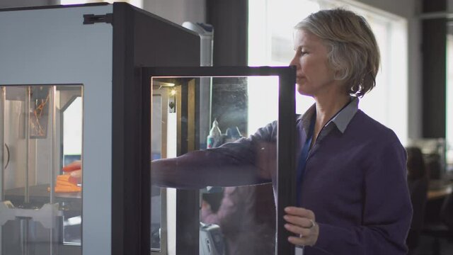Mature female college student studying engineering using 3D printing machine - shot in slow motion