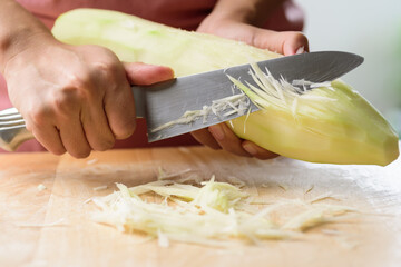 Hand holding knife and chopped green papaya fruit preparing for papaya salad cooking, Thai food