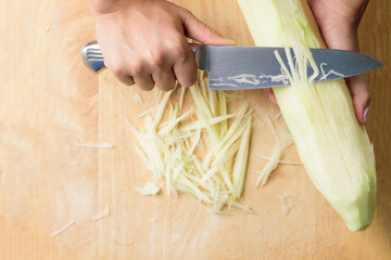 Hand holding knife and chopped green papaya fruit preparing for papaya salad cooking, Thai food