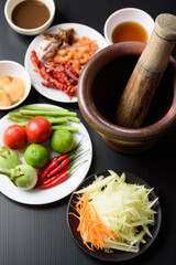 Thai cuisine, food ingredients and recipe for spicy papaya salad (Som Tum) on black background