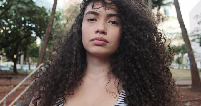 Young afro-american woman with curly hair looking at camera. Cute afro girl with curly hair looking at camera. 4K.