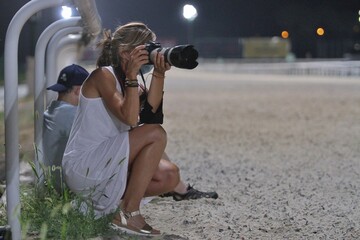 Mujer atractiva fotografiando en un hipódromo de carreras
