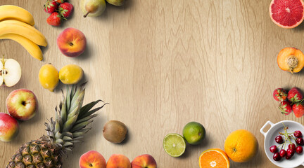 Colorful fresh fruit on wood table. Orange, strawberries, lemons, peach slice, grapefruit, limes, pears, kiwi. Summer fruit. Flat lay, top view