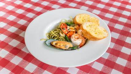 Spaghetti al pesto with chili shrimp and mussels on white plate