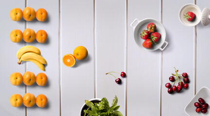 Yellow fruits on a wooden background. Red and Orange Fresh Fruit on white wood table flat lay top view. Orange, appricots, banana, strawberry, cheery and plums