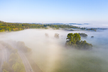 sunrise over meadows and road in the morning fog