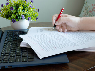 hand holding red pen on paperwork