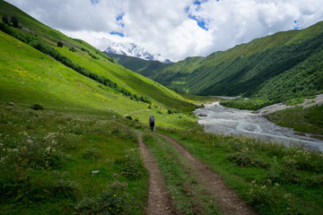 Fototapeta na wymiar Touristic hiking trails through the green mountains, snowy peaks and rivers in Georgia