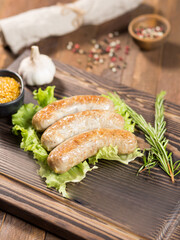 Fried sausages on a wooden board with salad, tomatoes, sauces and beer
