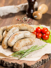 Fried sausages on a wooden board with salad, tomatoes, sauces and beer