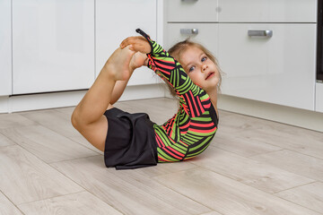 beautiful girl 4 years old in a gymnastic leotard is engaged in gymnastics at home in the kitchen....