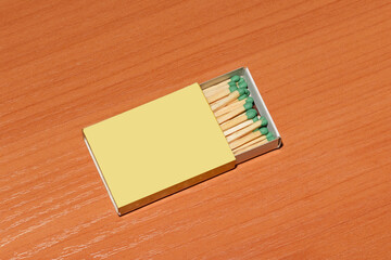 A half-open matchbox with matches lying flat on a wooden table.