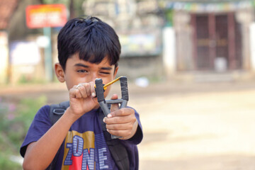 Portrait of Indian little boy holding a Catapult	
