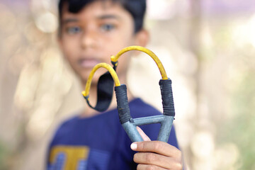 Portrait of Indian little boy holding a Catapult	
