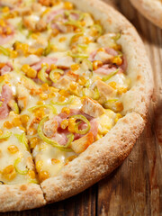 Pizza with pineapple on a wooden background, close-up, cherry tomatoes